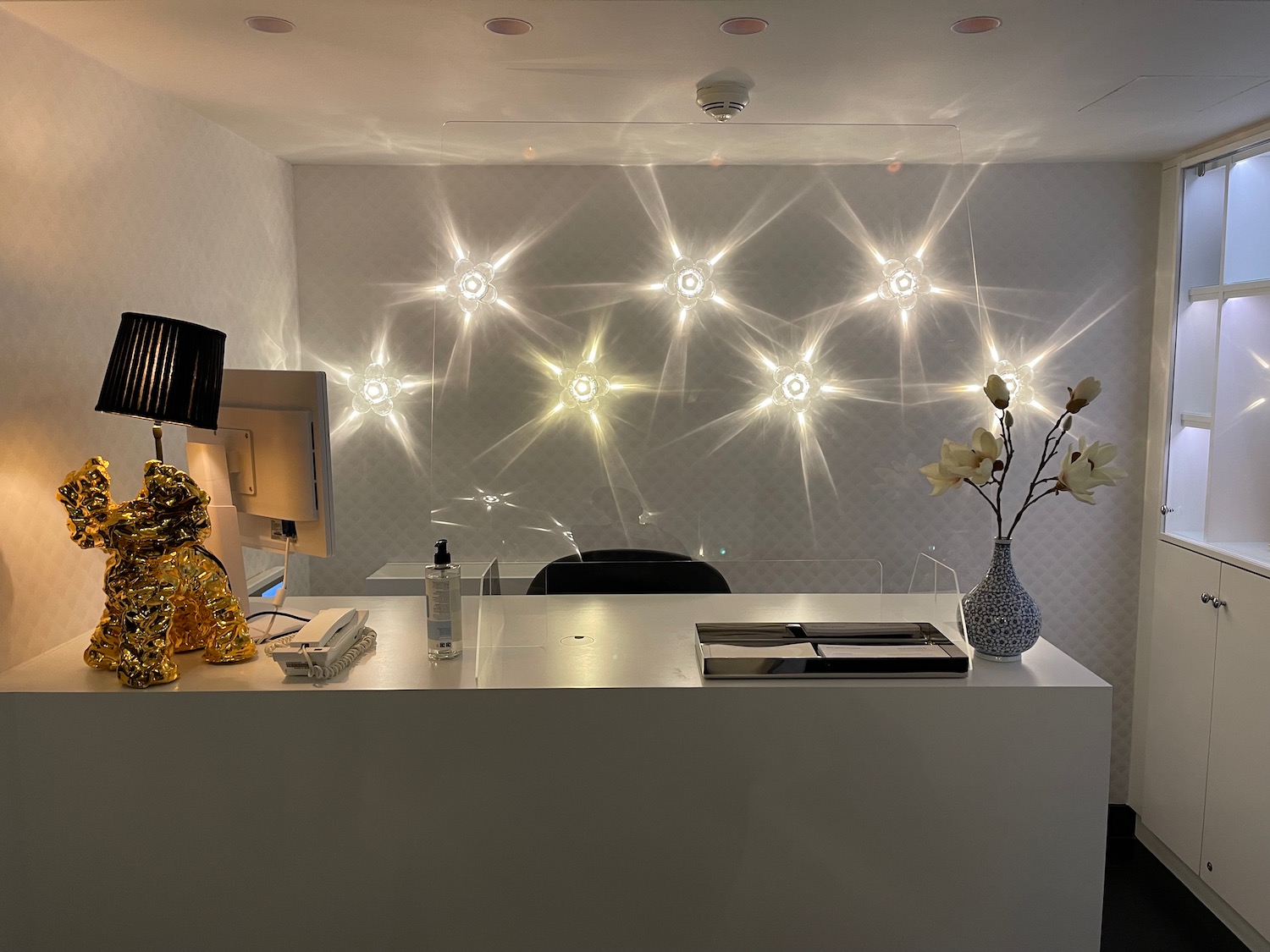 a desk with a vase of flowers and lights on the wall