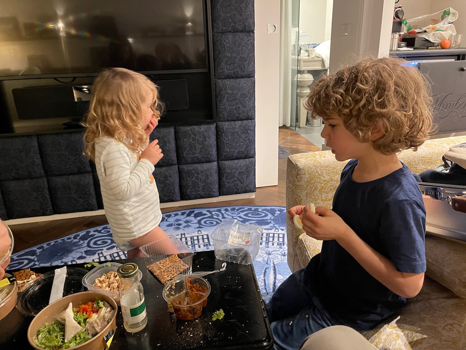 a boy and girl eating food in a living room