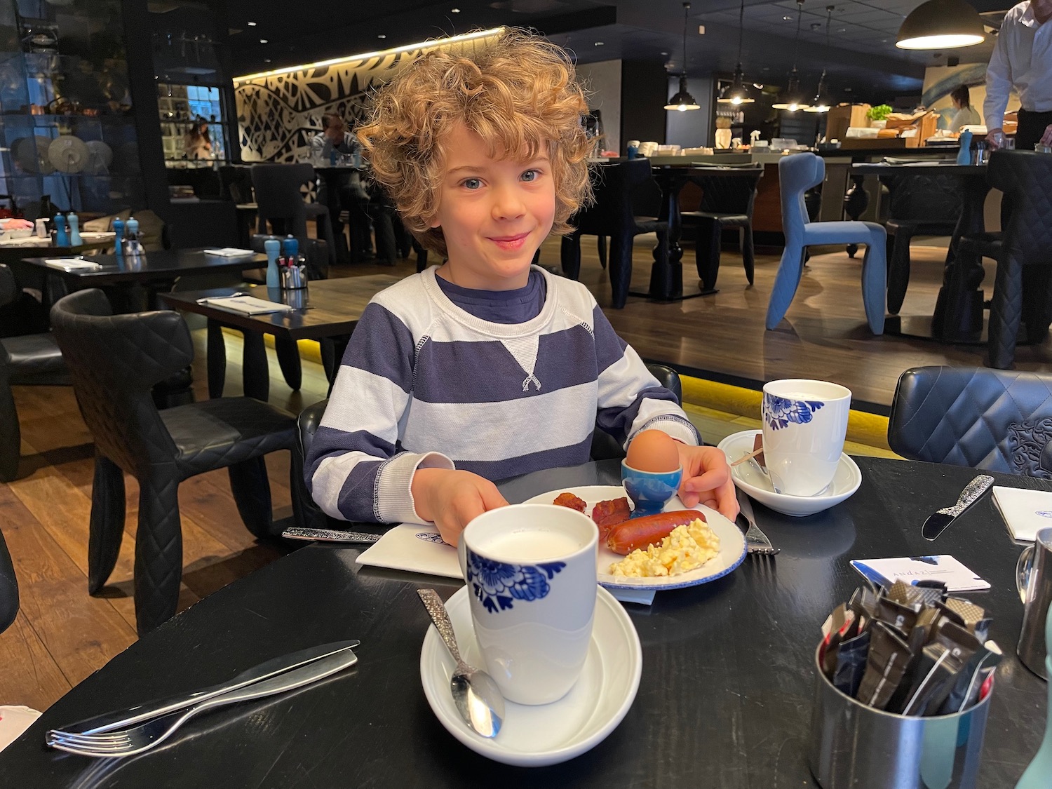 a boy sitting at a table with a plate of food