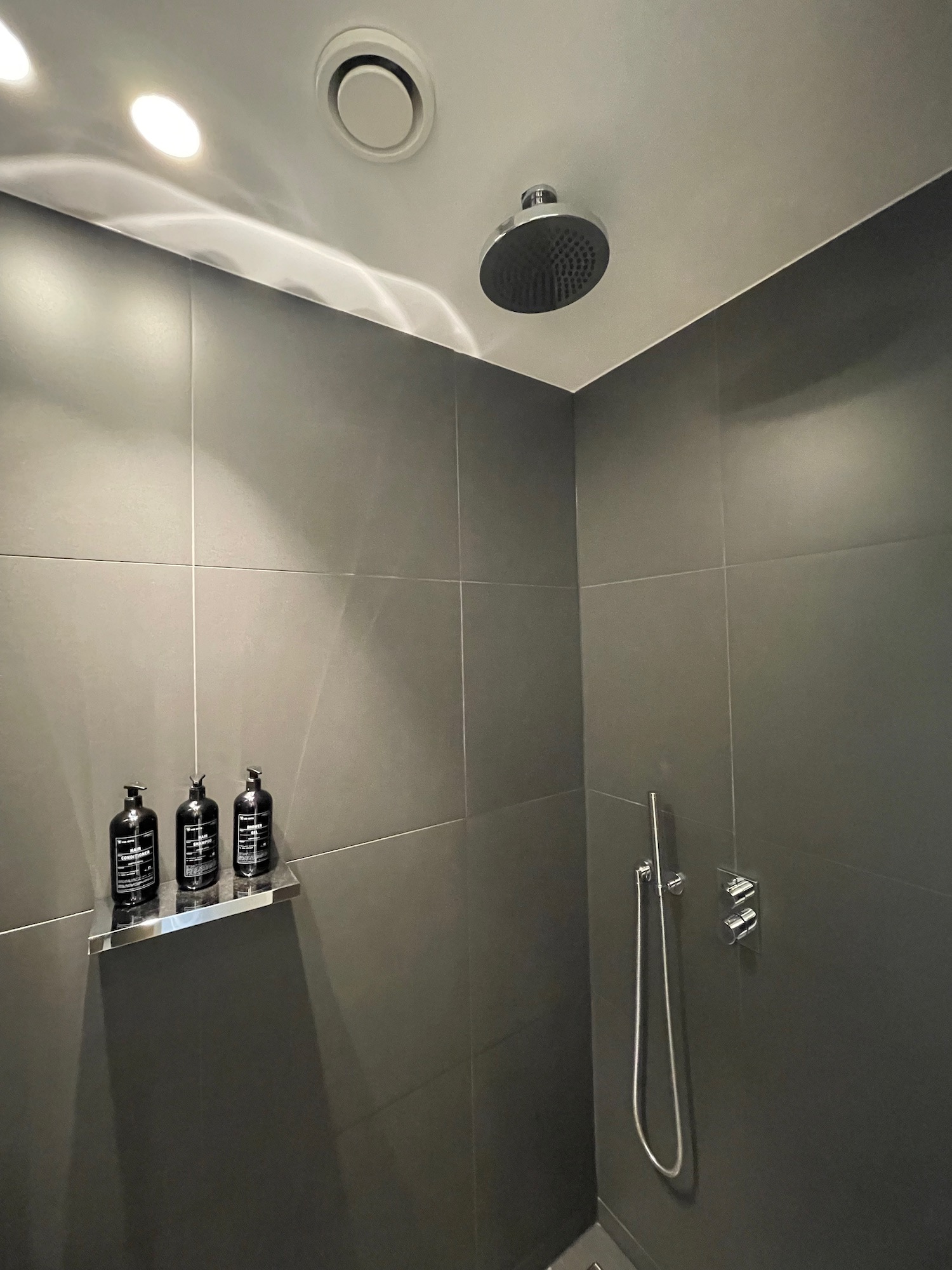 a shower with a shower head and bottles of shampoo