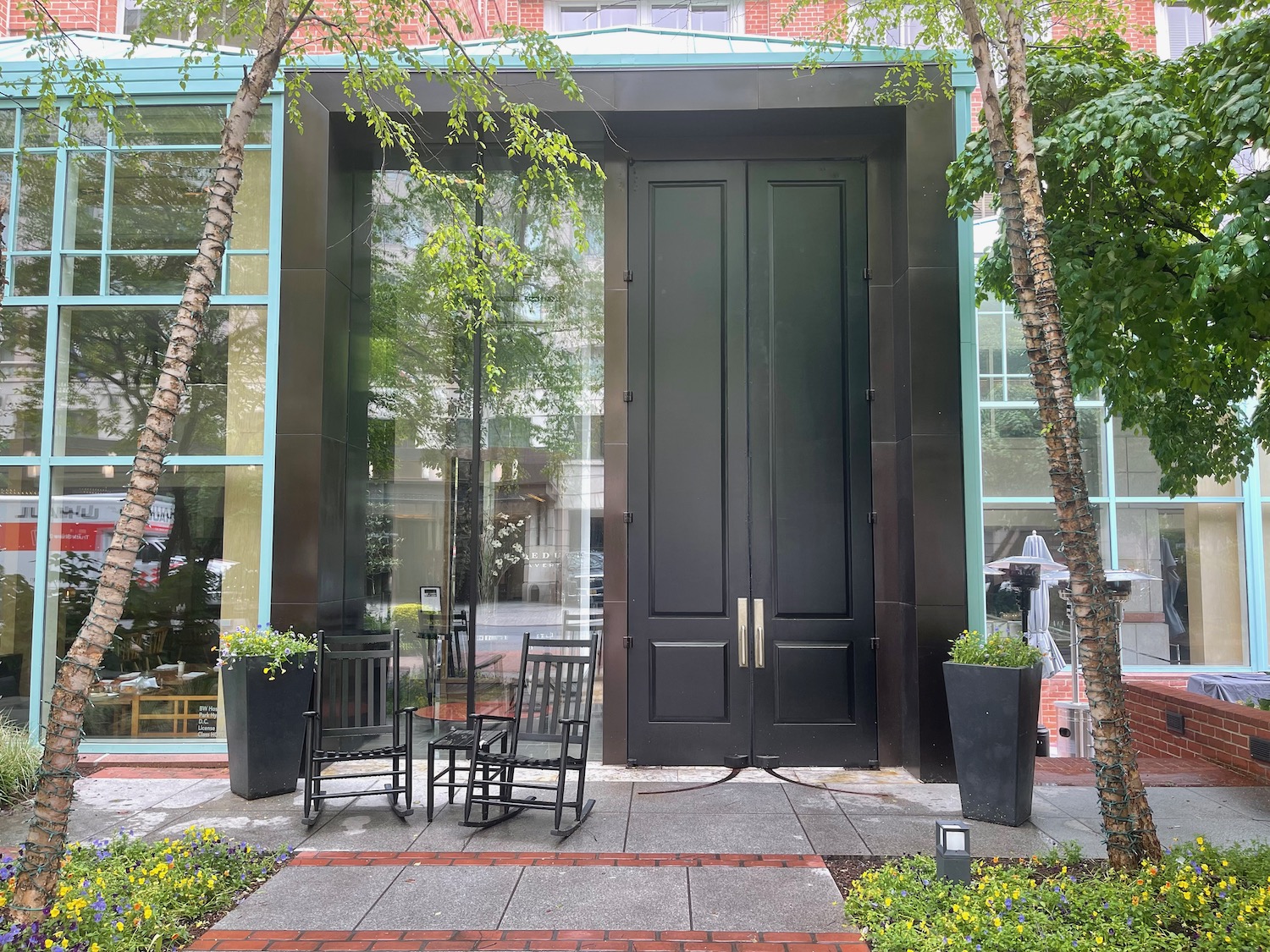 a black door with chairs and a table in front of a building