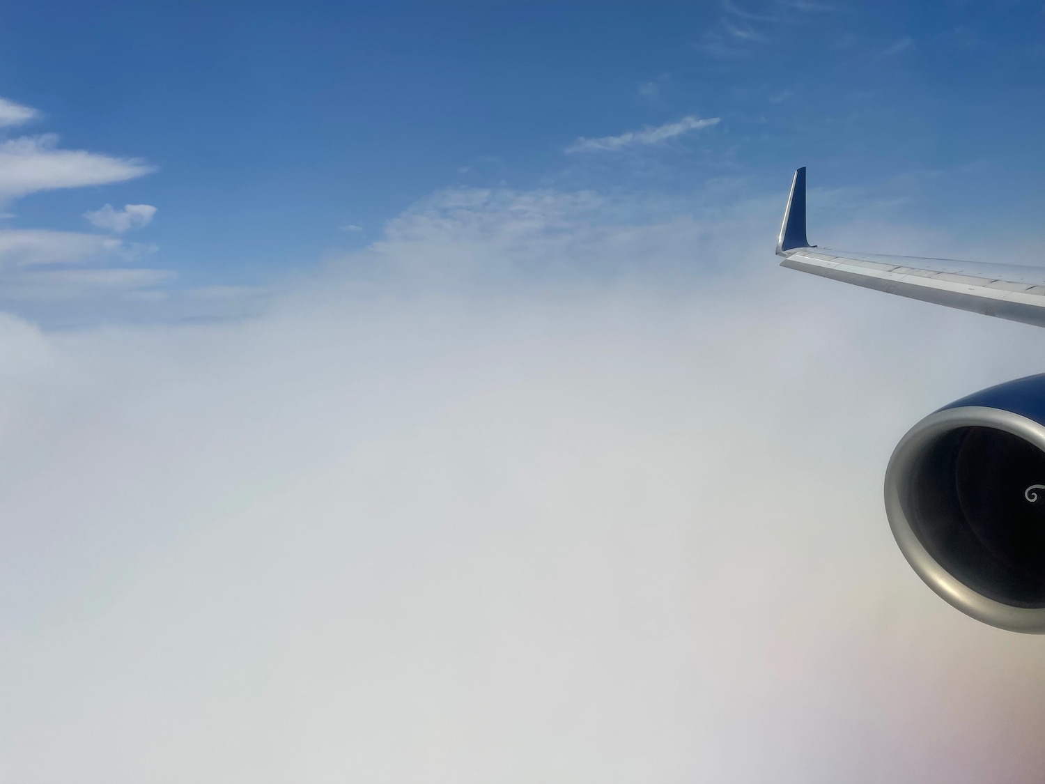 a wing of an airplane flying above clouds