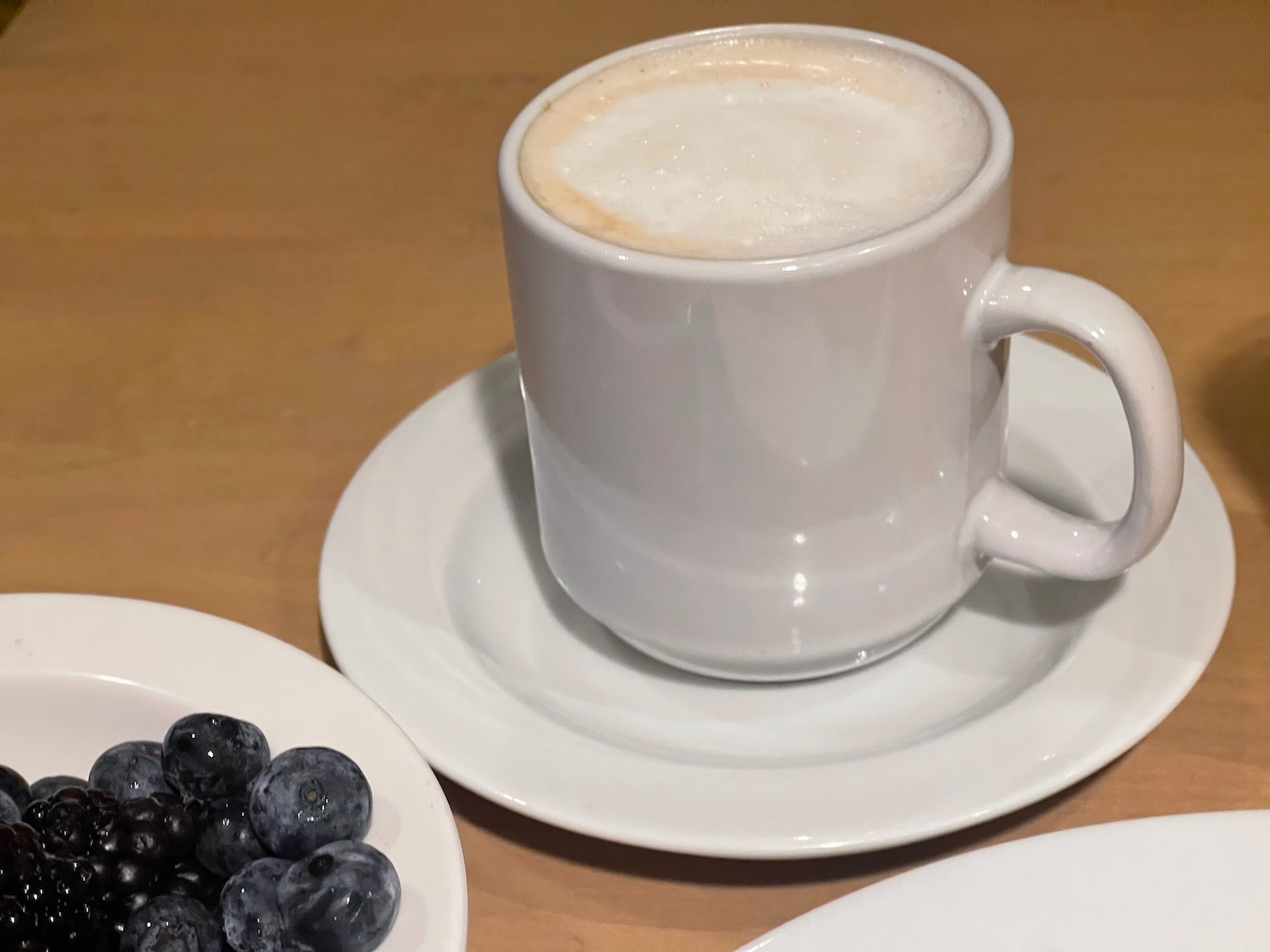 a cup of coffee and a plate of blueberries