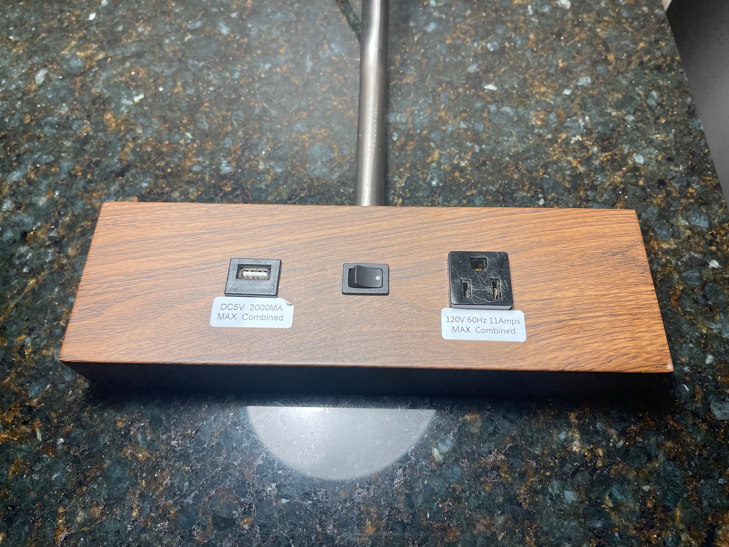 a wood block with black square buttons on a black metal pole