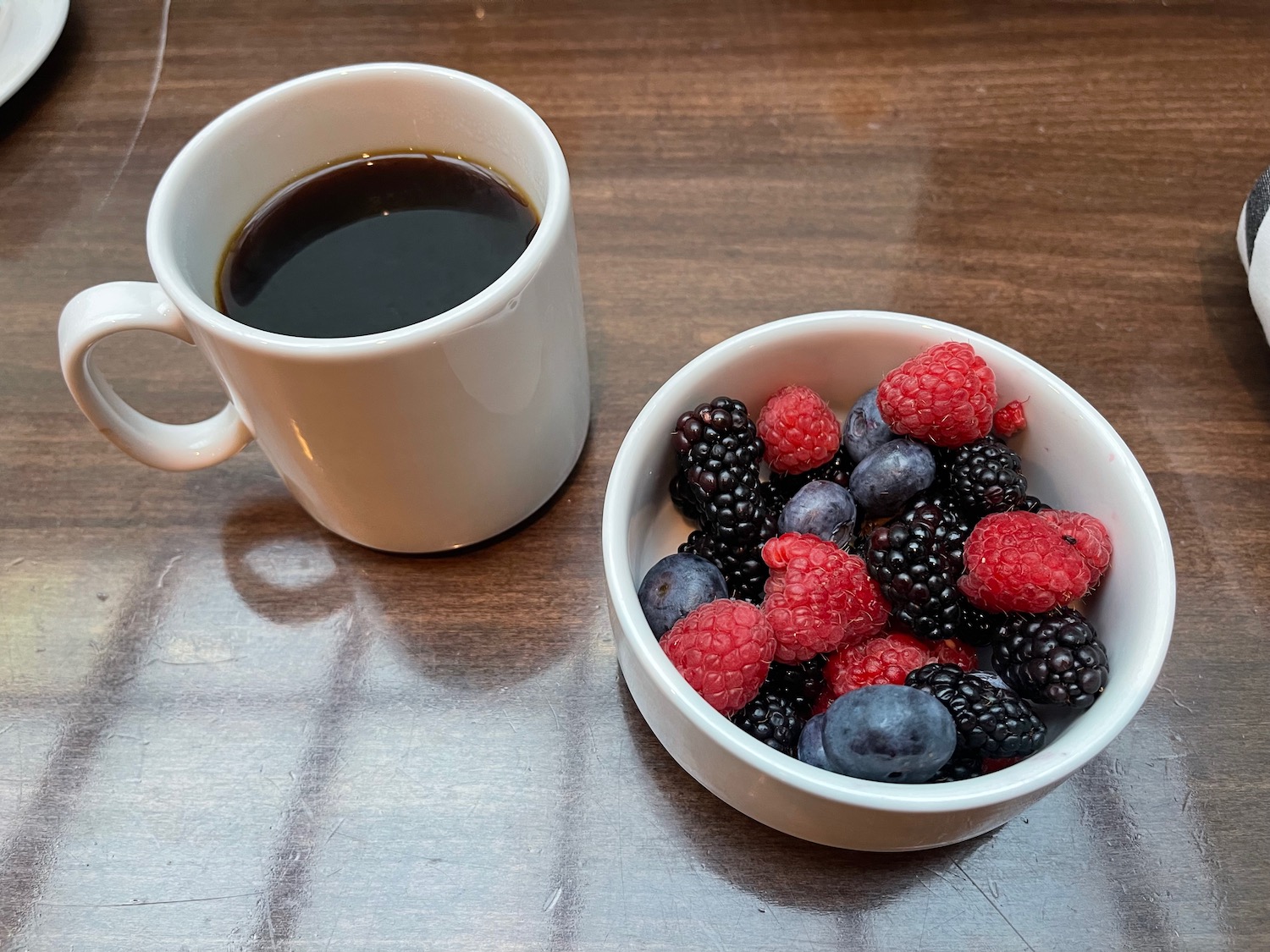 a bowl of berries and a cup of coffee