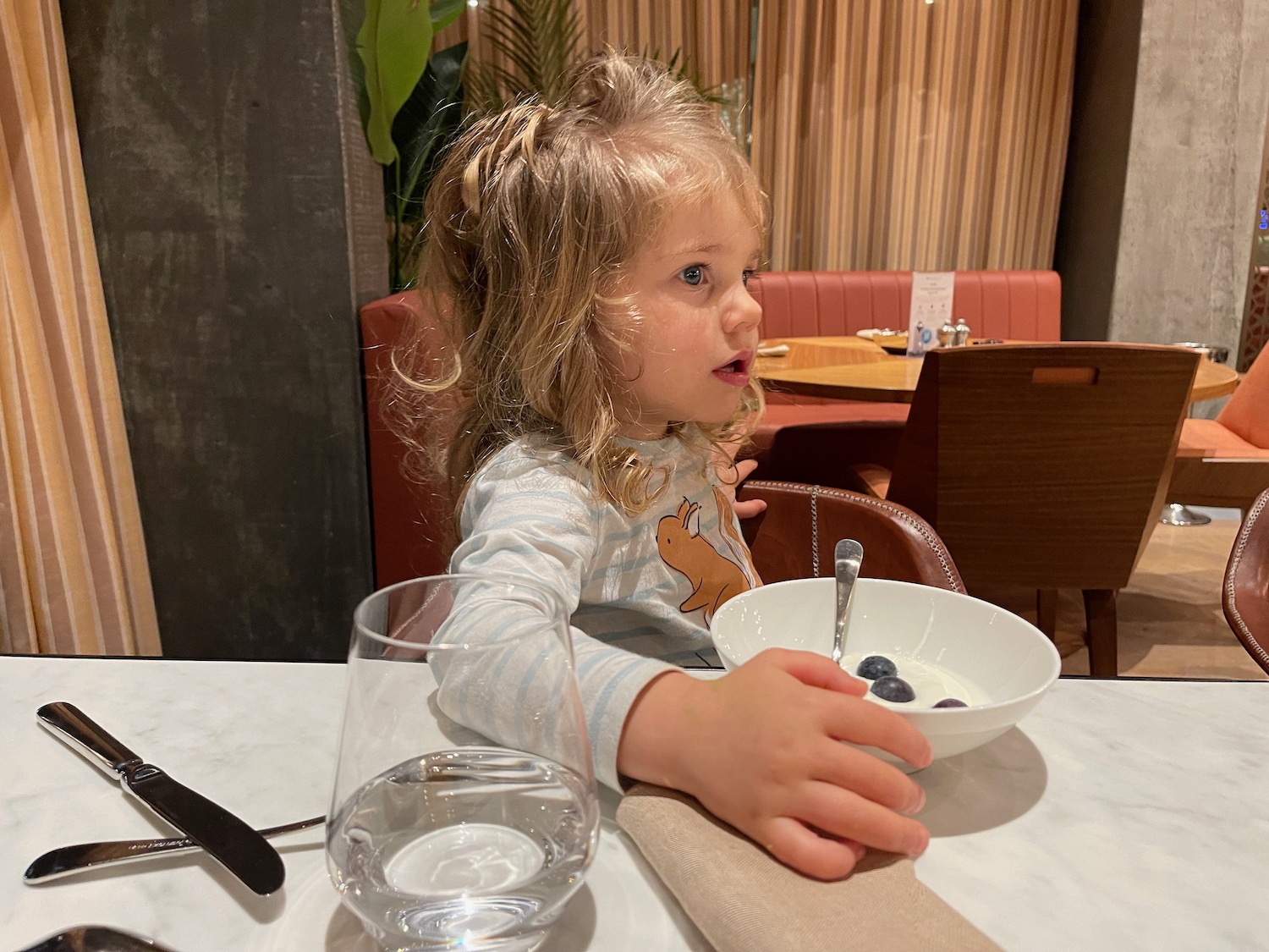 a girl sitting at a table with a bowl of cereal