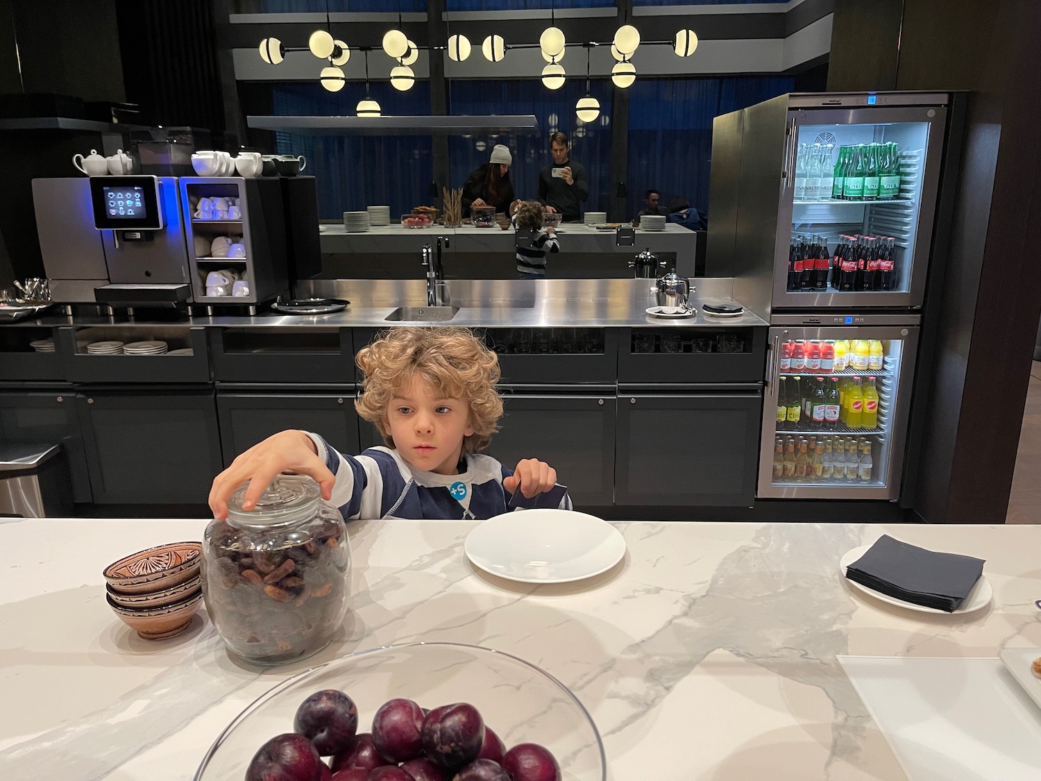 a boy sitting at a table with a jar of food