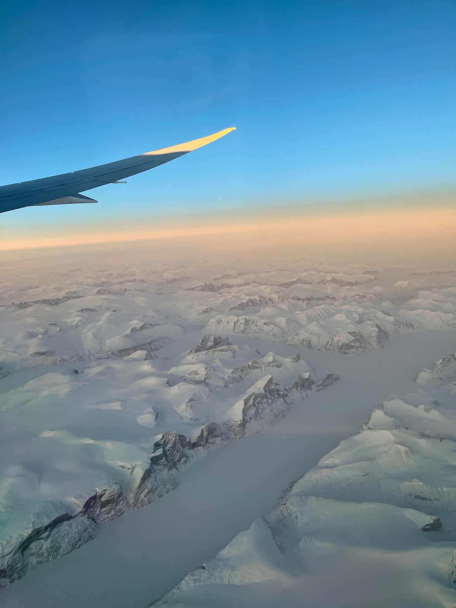 an airplane wing above a snowy landscape