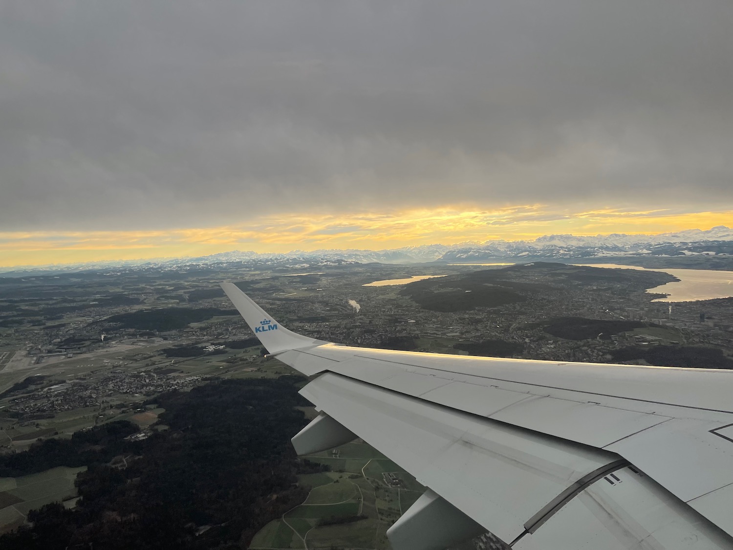 an airplane wing and view of a city and mountains