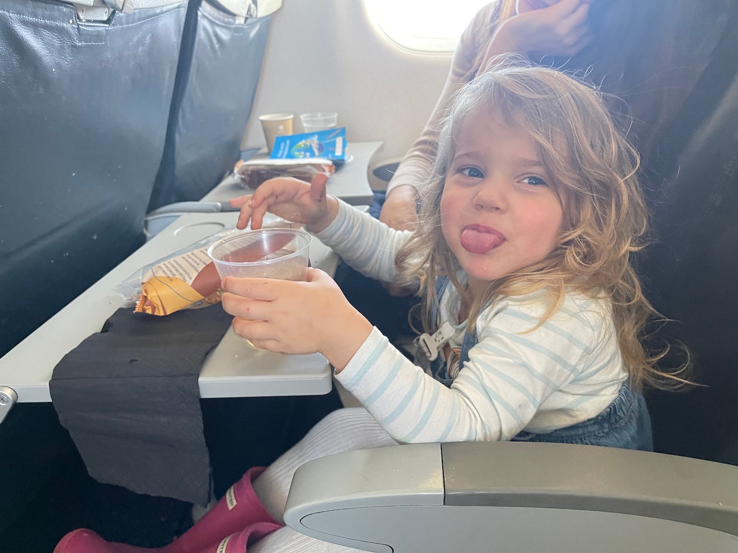 a child sitting in an airplane with her tongue out