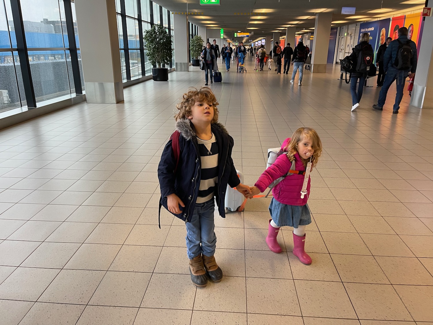 a couple of children holding hands in a large building