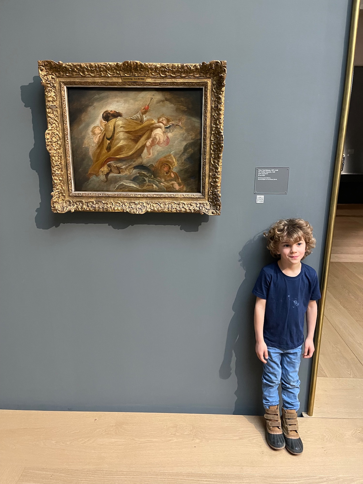 a boy standing next to a painting on a wall