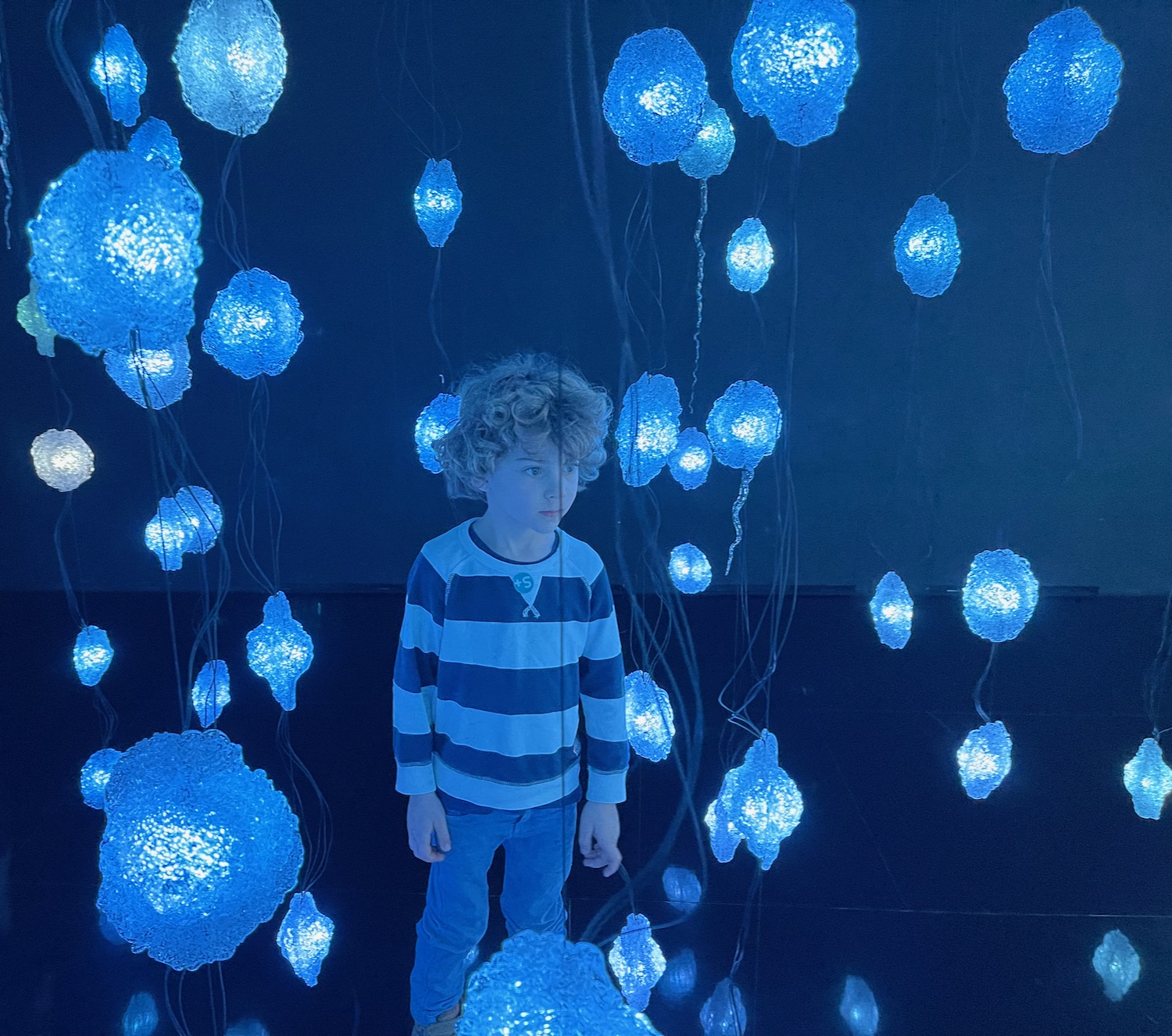 a boy standing in front of many blue lights