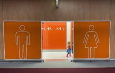 a girl standing in front of a man and woman toilet