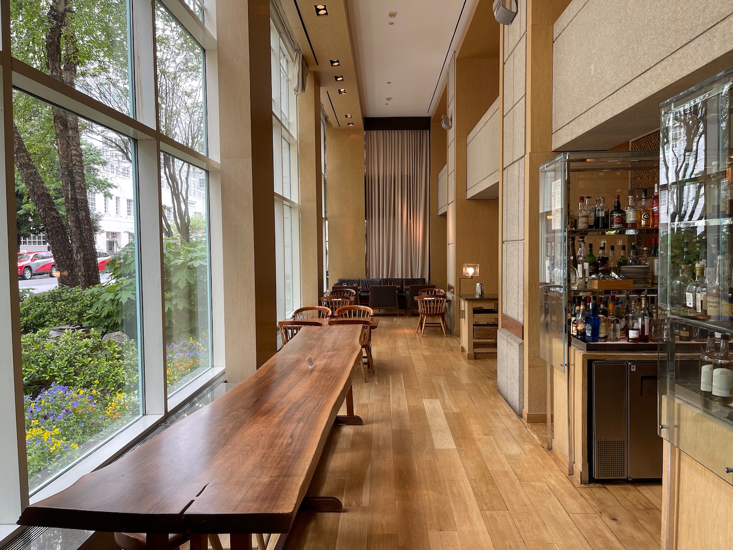 a long wooden table in a room with a glass case and a bar