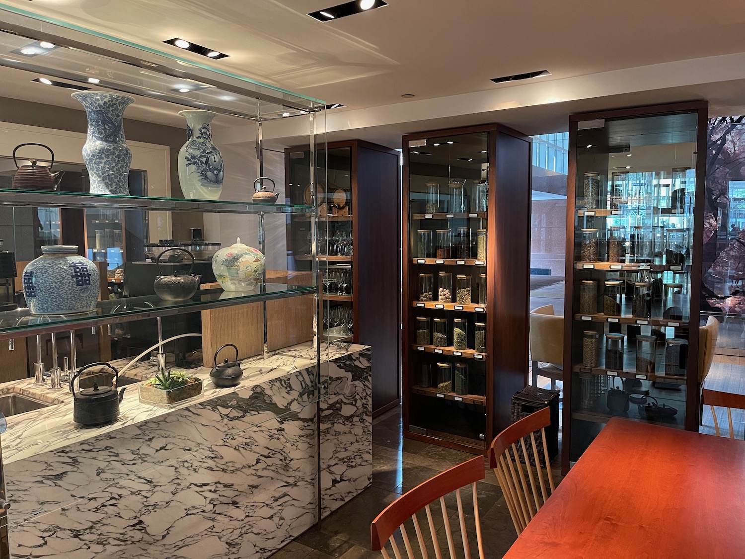 a room with a table and chairs and a table with glass shelves