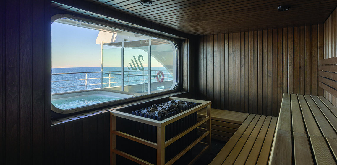 a sauna with a hot tub and a window overlooking the water