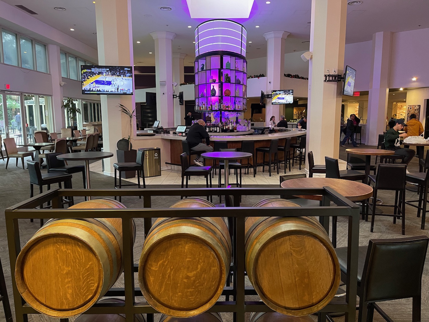 a room with tables and chairs and a bar with a purple light