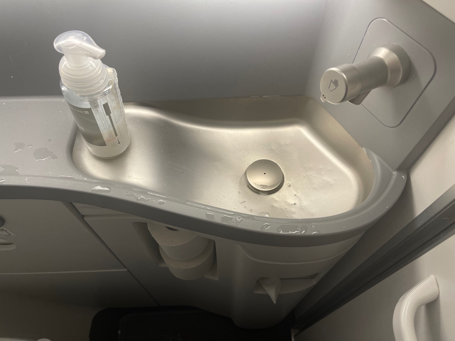 a sink with soap dispenser and a bottle on it