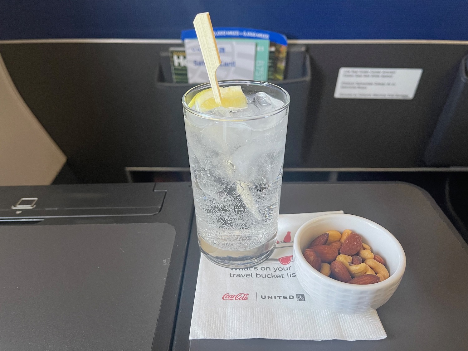 a glass of water with a slice of lemon and a bowl of nuts