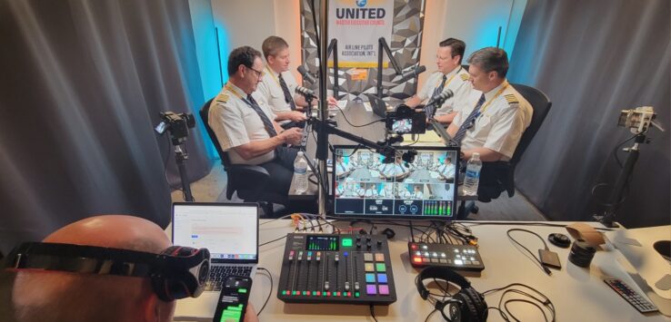 a group of men in a room with a microphones and a camera