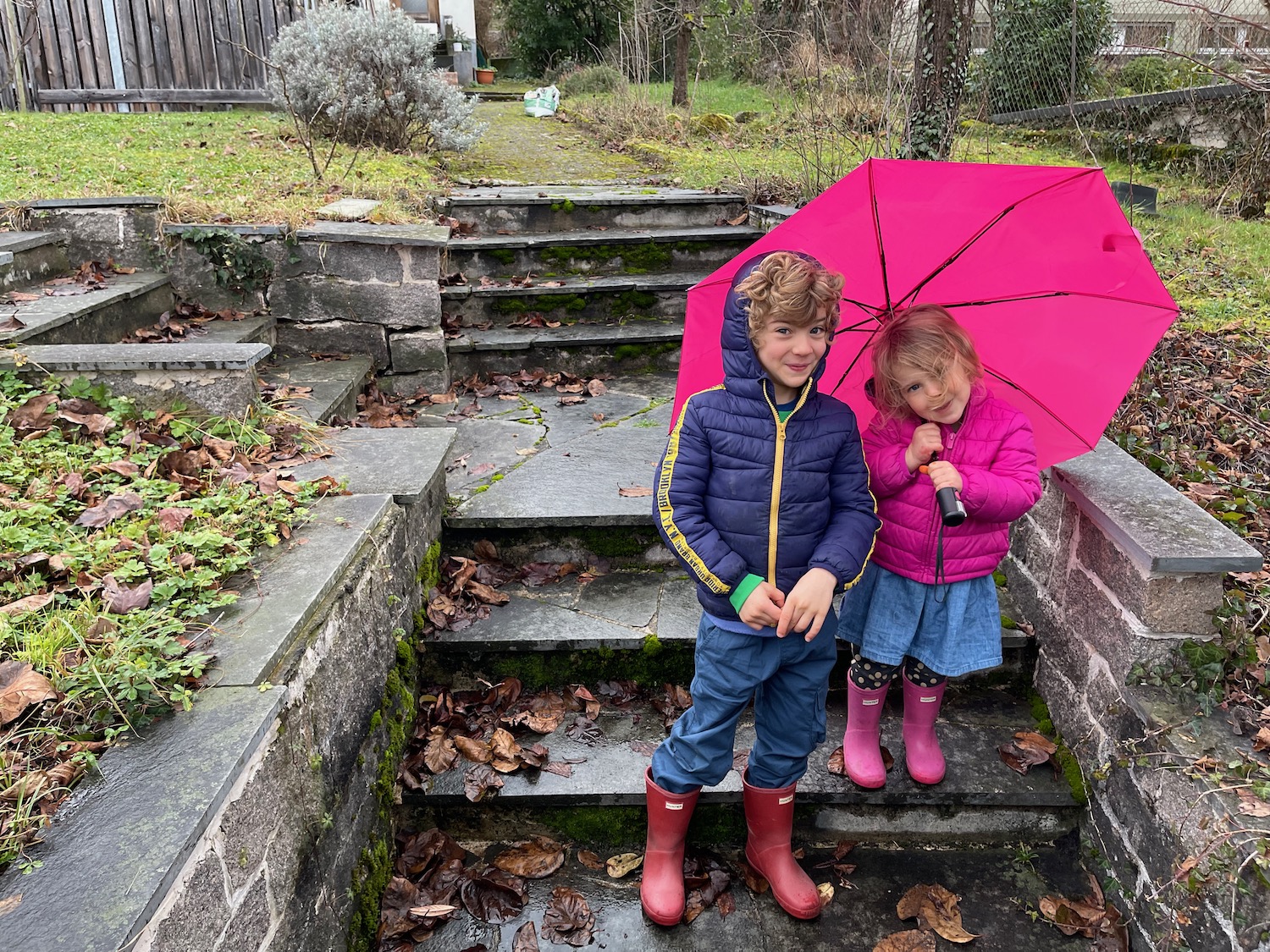 a boy and girl standing on steps with umbrella