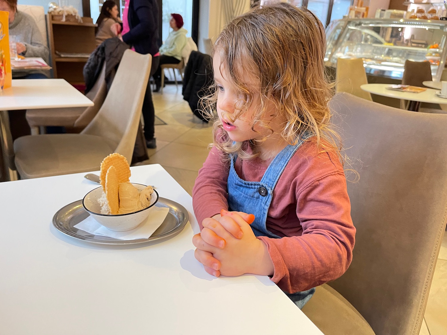 a girl sitting at a table with a bowl of ice cream