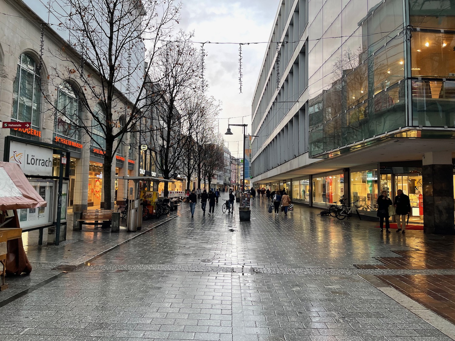 a wet street with people walking on it