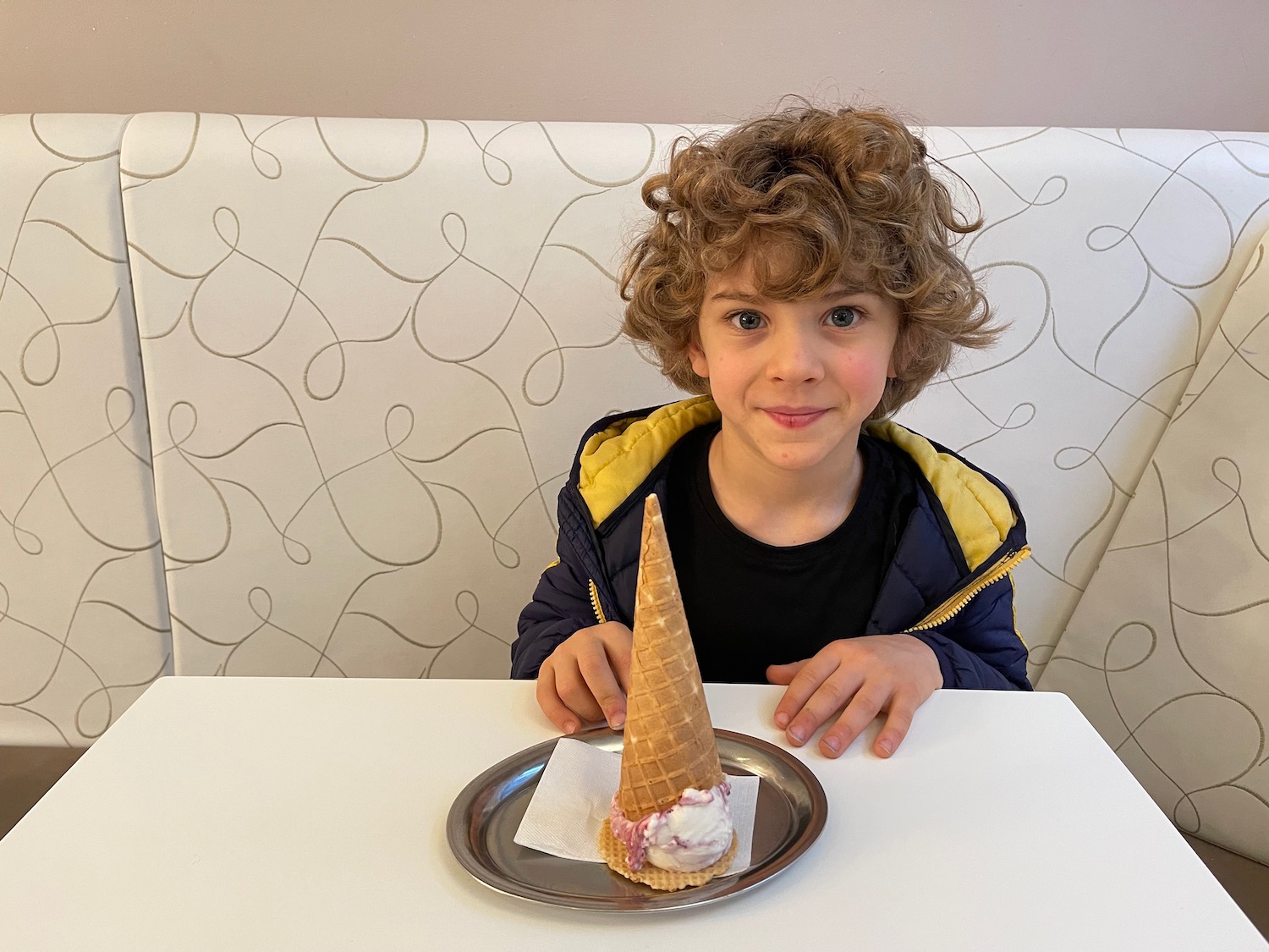 a boy sitting at a table with a plate of ice cream