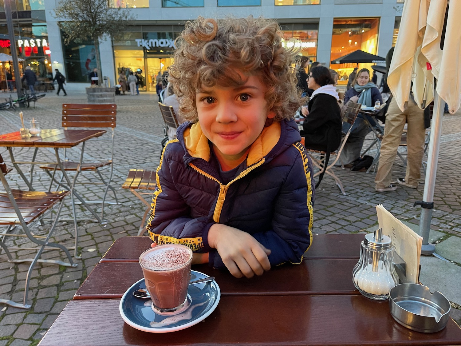 a boy sitting at a table with a drink