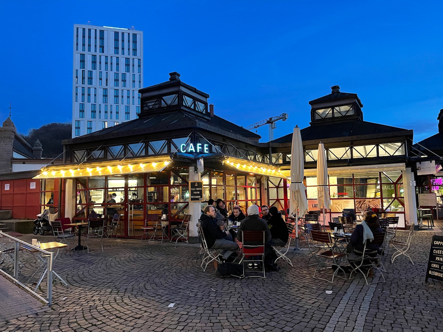 a group of people sitting at tables outside a cafe