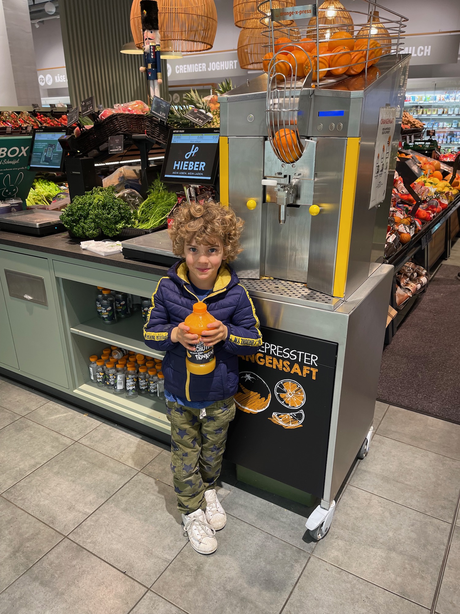 a child standing next to a juice dispenser