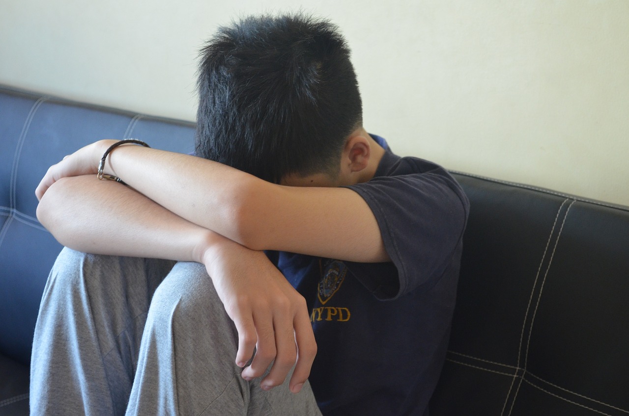 a man sitting on a couch with his head on his knees