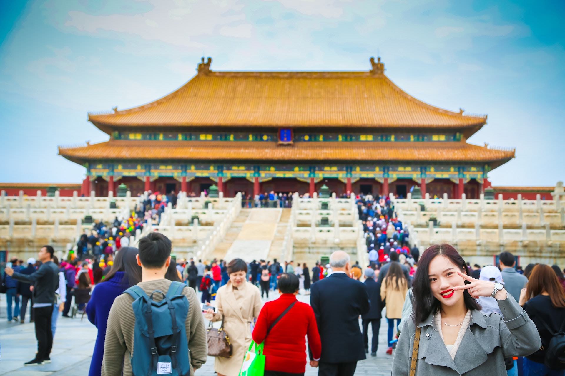 a woman standing in front of a large building with Forbidden City in the background