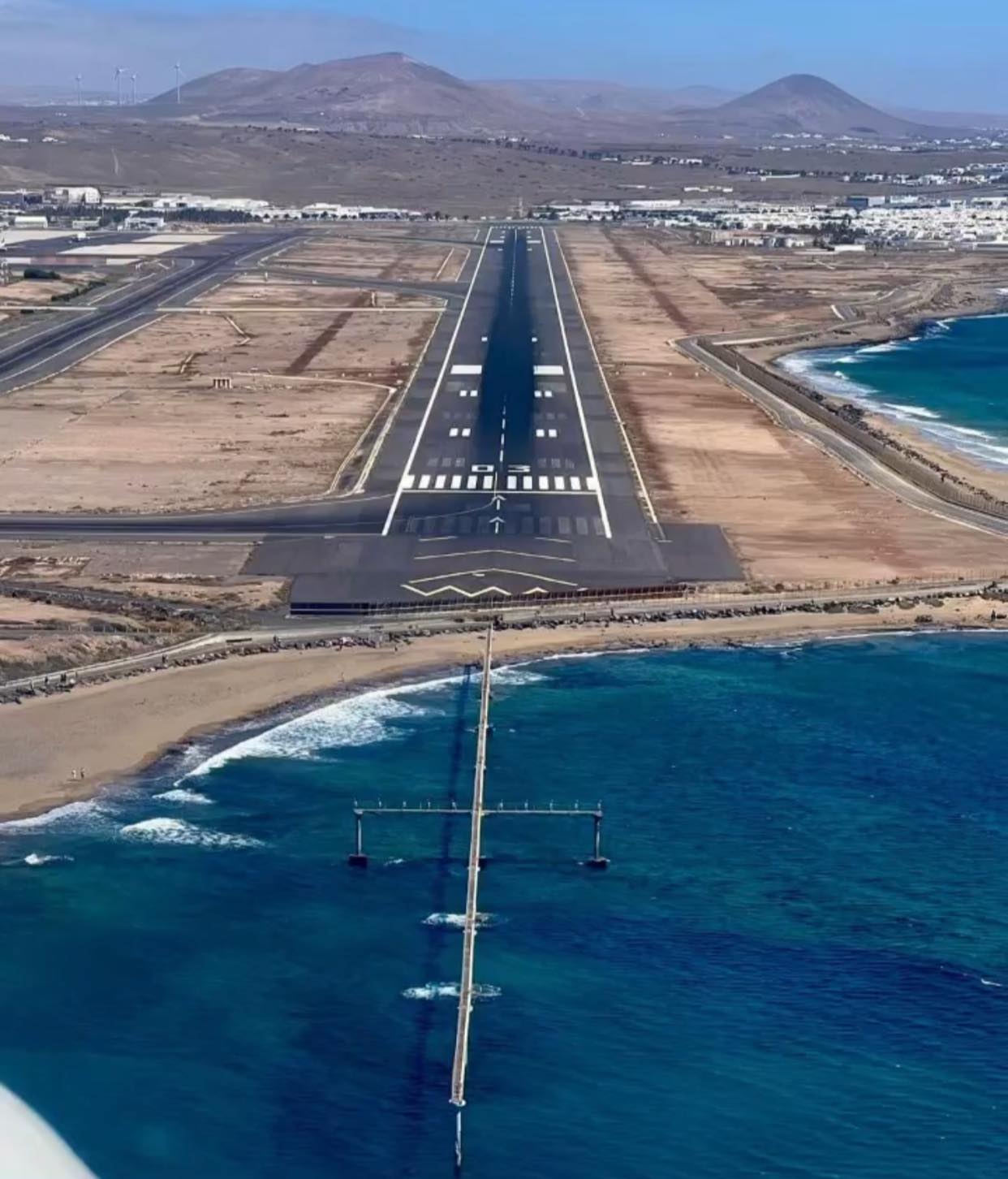 an airport runway with a body of water and mountains in the background