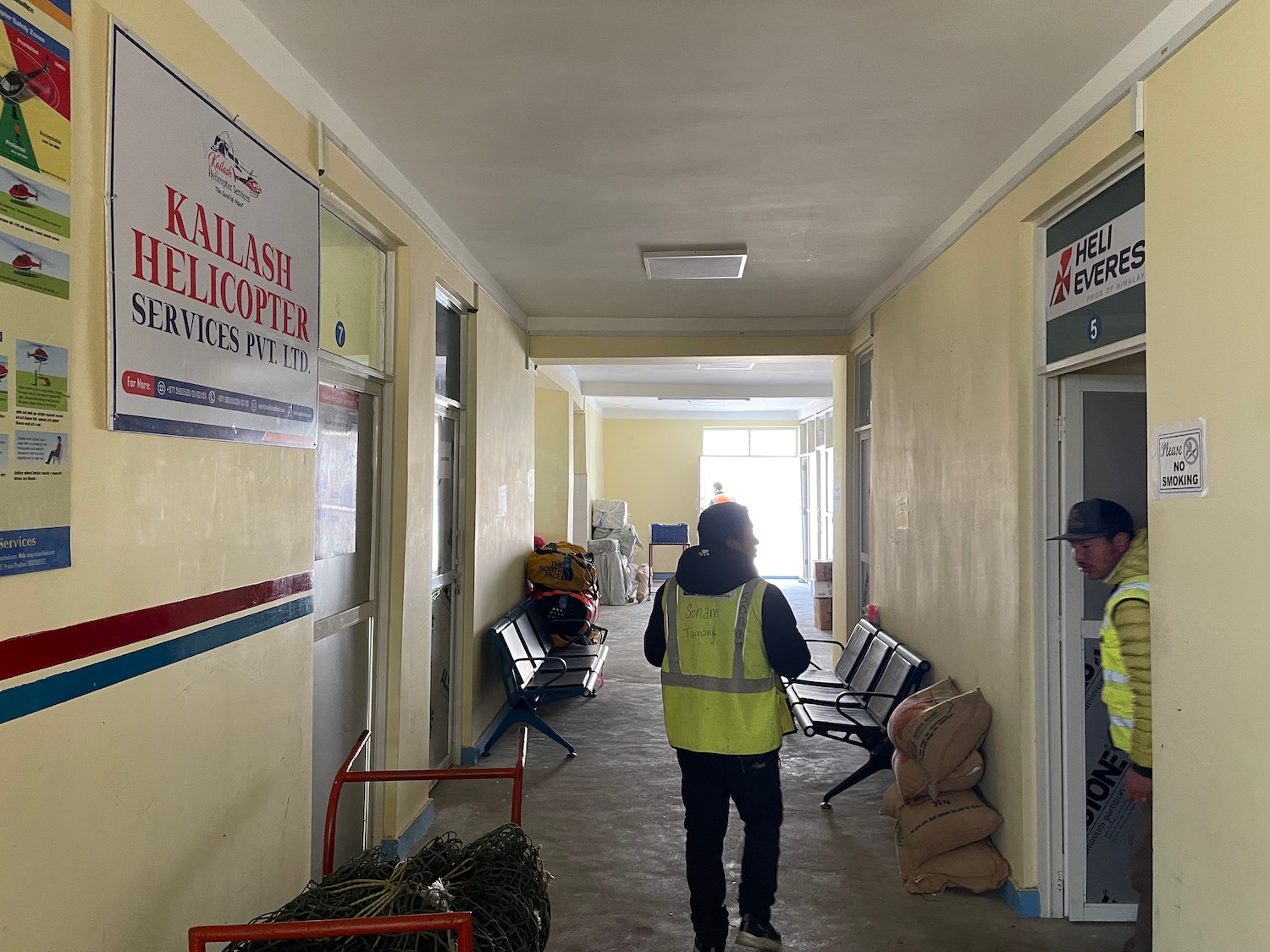 a man in a yellow vest walking in a hallway