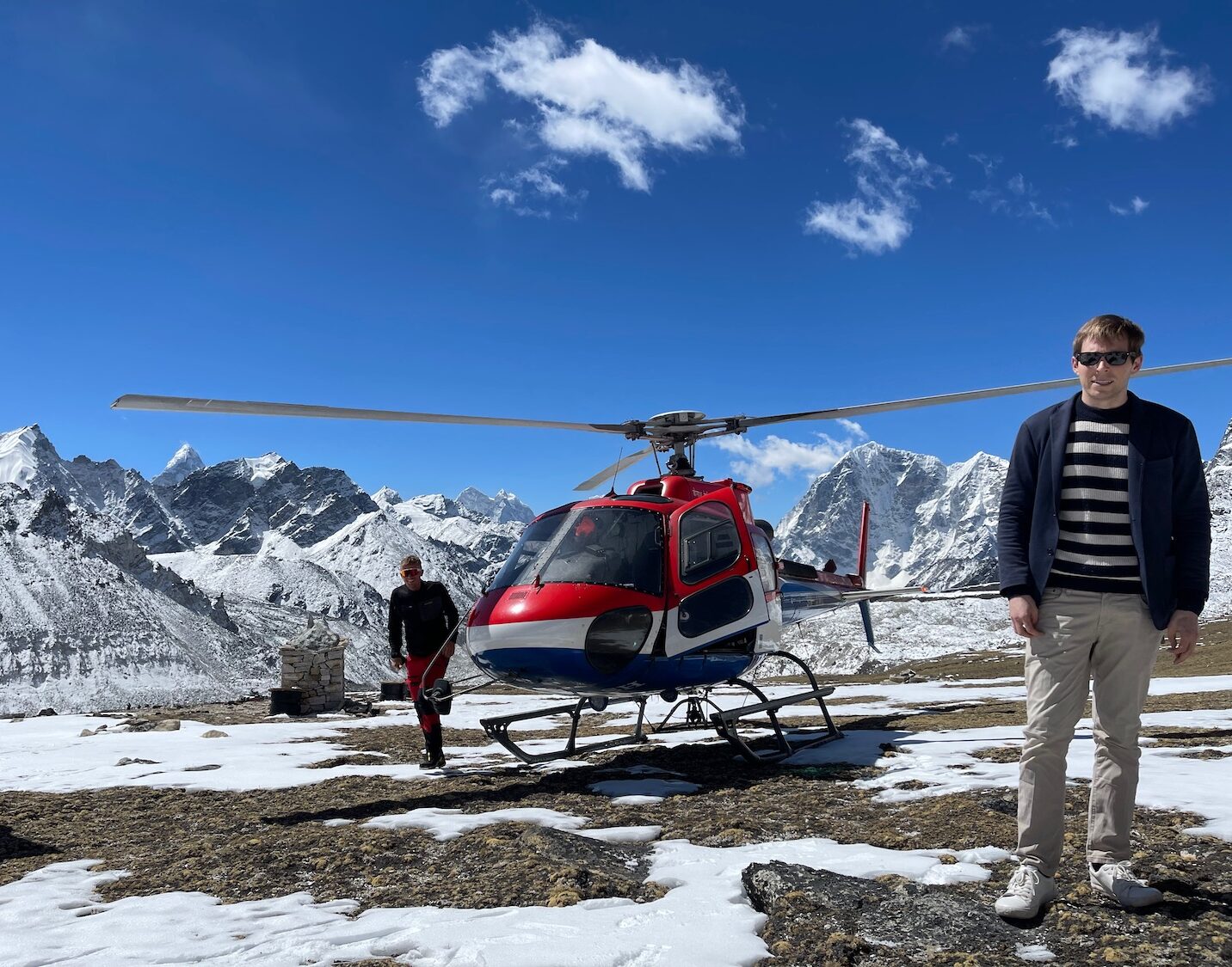 a man standing next to a helicopter on a snowy mountain