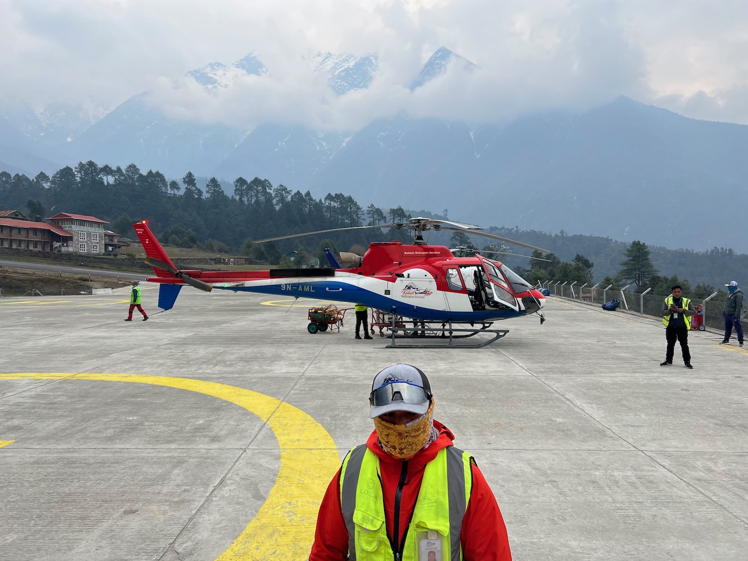 a person standing on a runway with a helicopter in the background