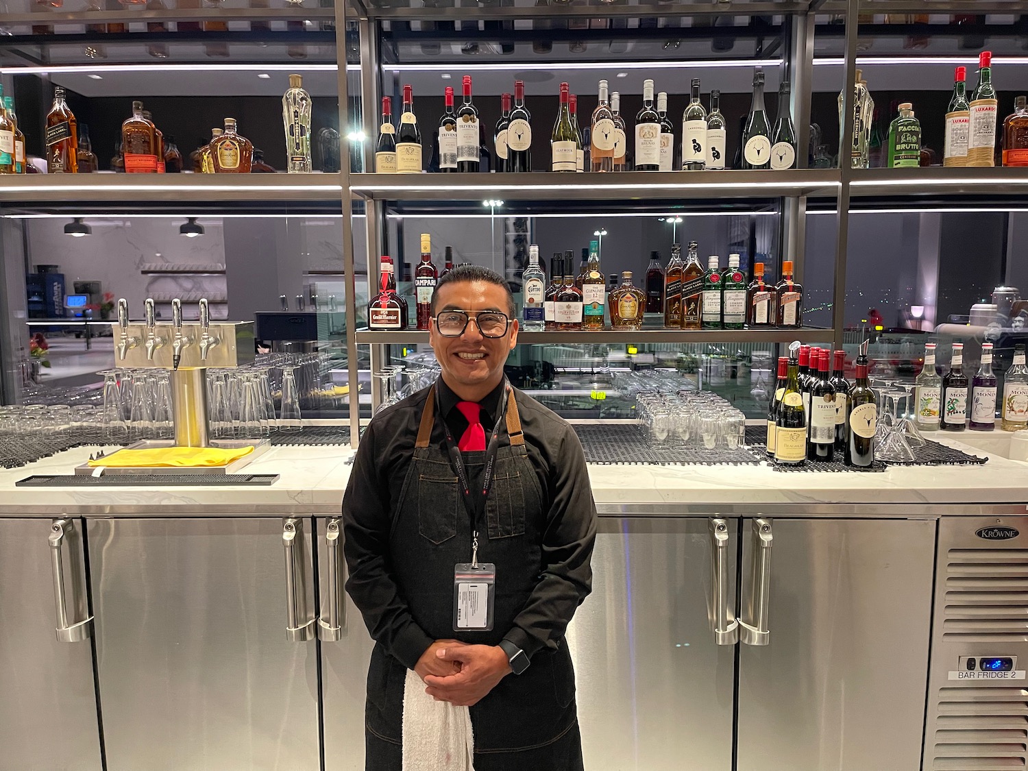 a man standing in front of a bar with bottles of alcohol