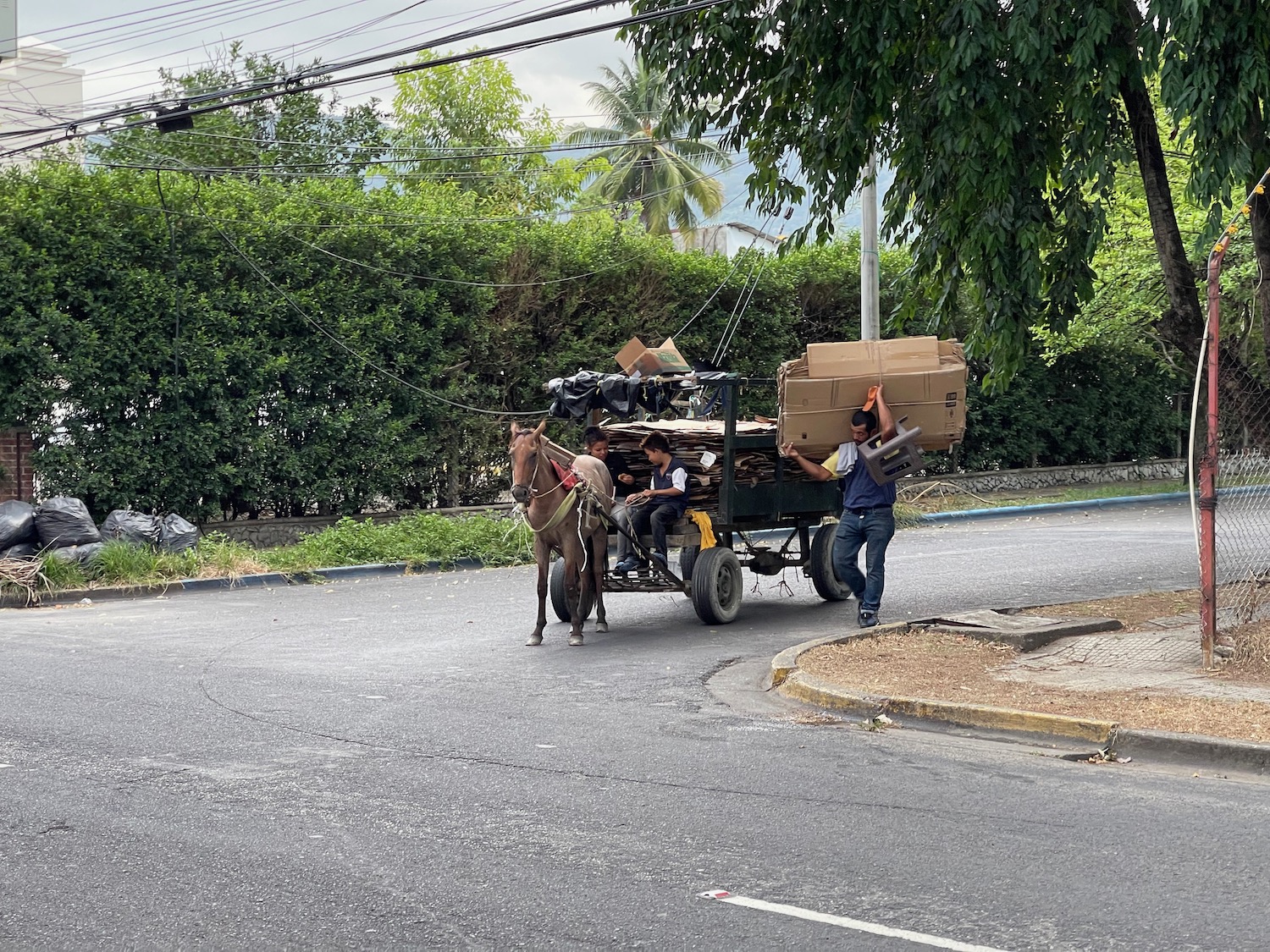 a horse pulling a cart with boxes and people on it