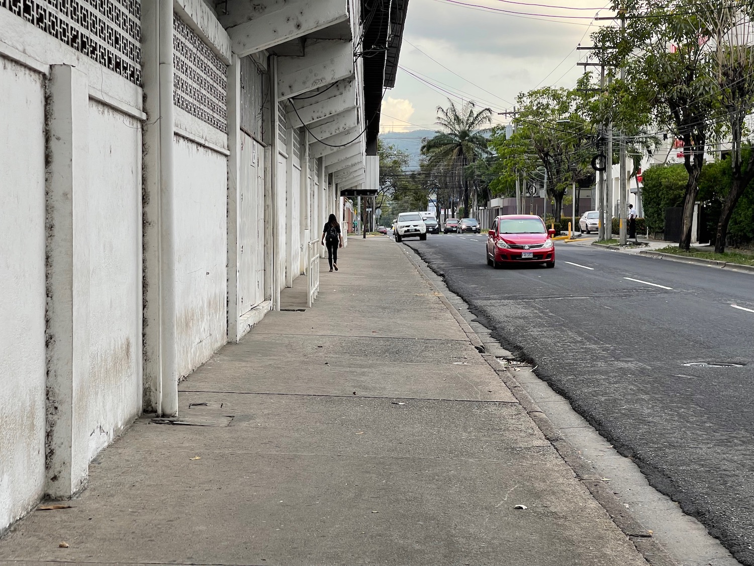 a person walking on a sidewalk next to a building