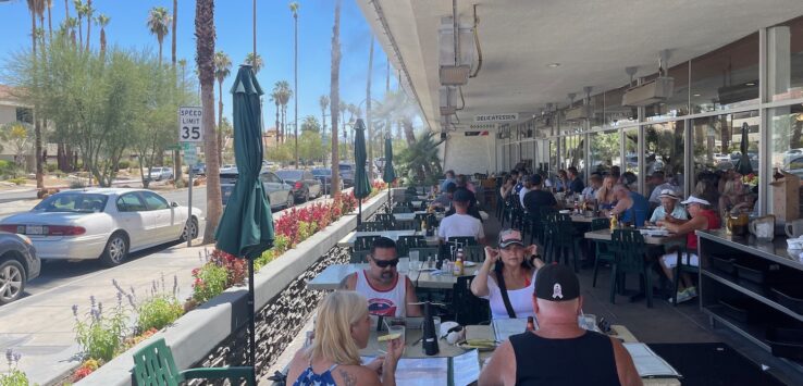 a group of people sitting at tables outside a restaurant