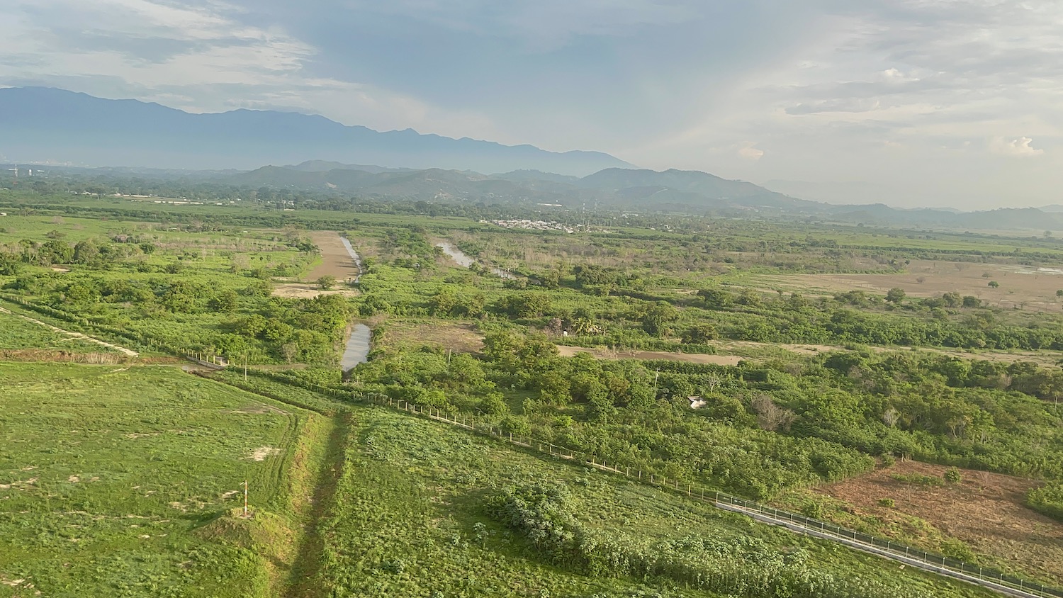 a green field with trees and mountains in the background