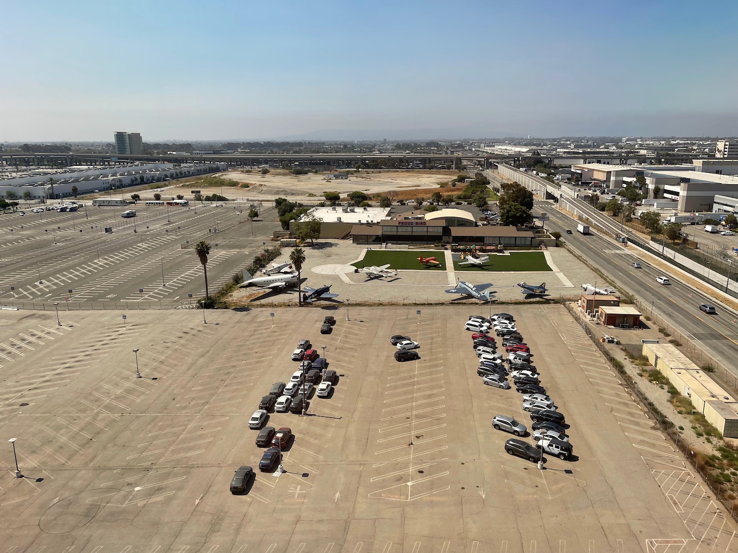 a parking lot with cars and planes in the background