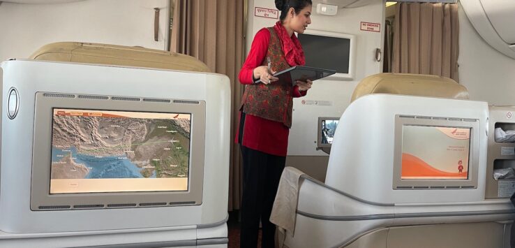 a woman standing in an airplane with a laptop