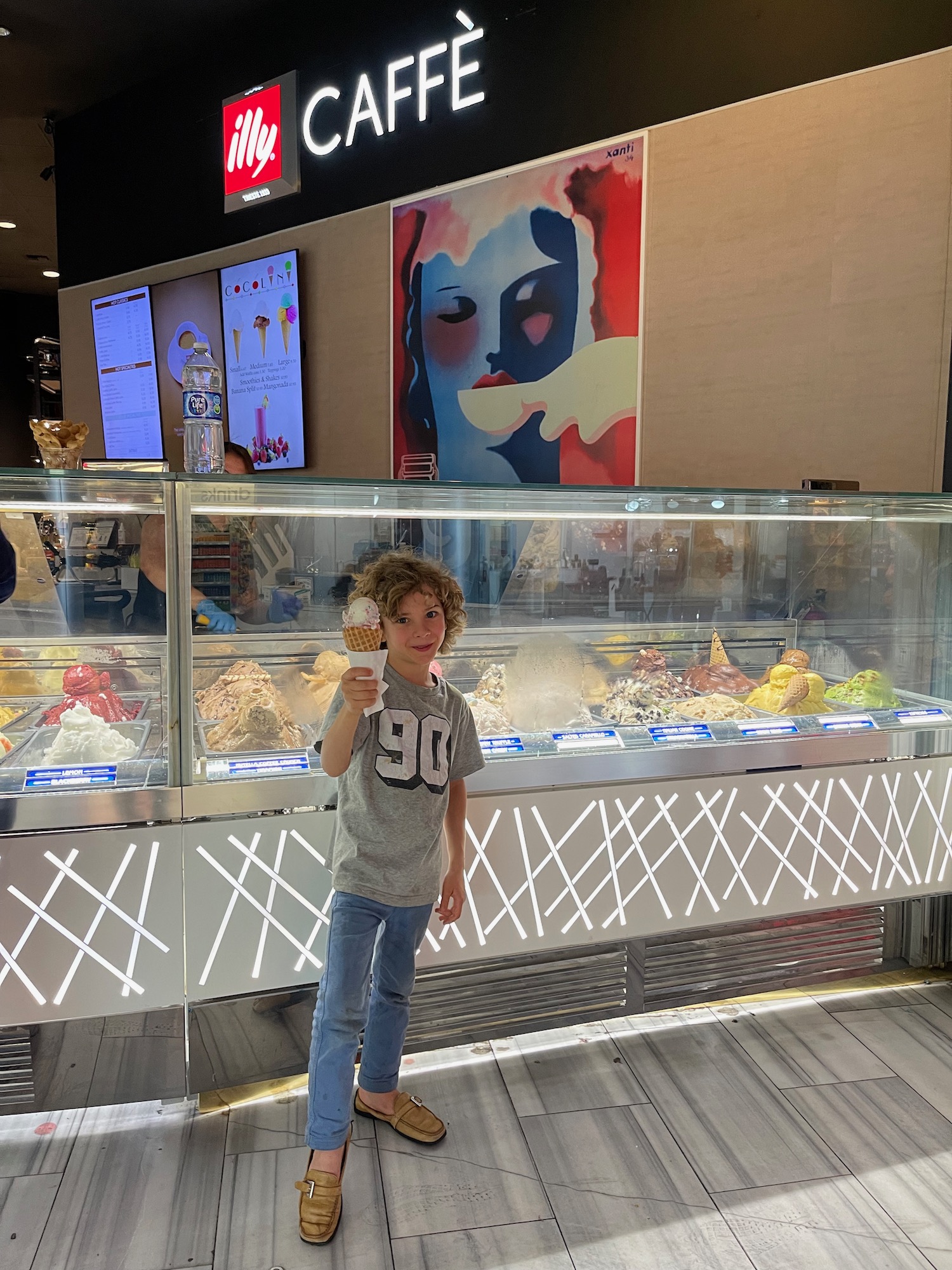 a boy holding an ice cream cone in front of a display case