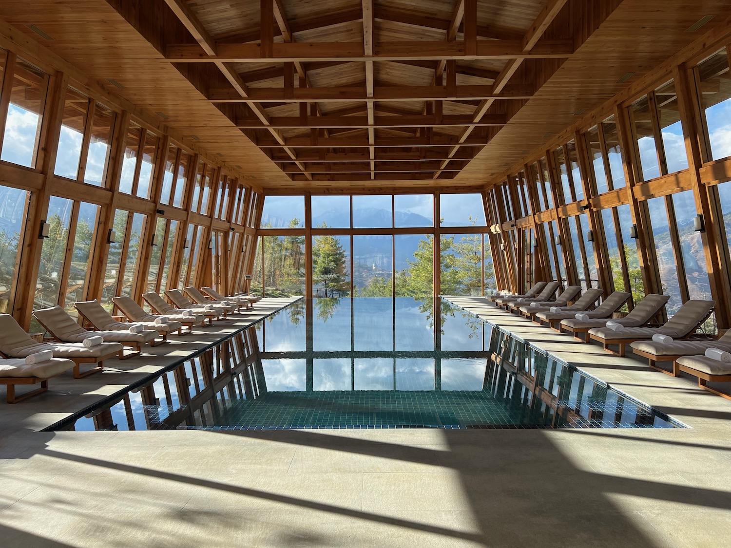 a pool inside a building with chairs and a view of mountains