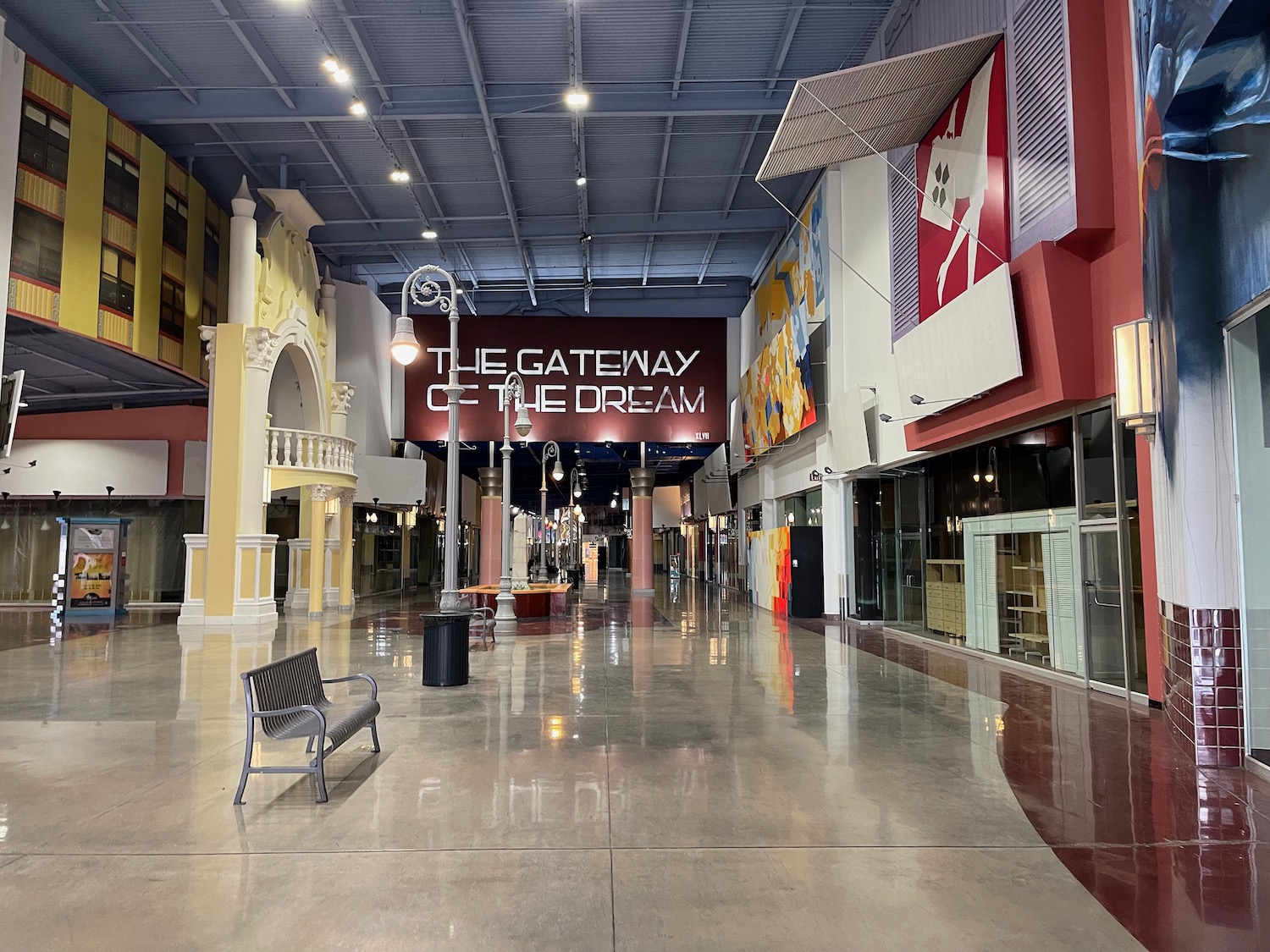 a large empty mall with a bench and signs