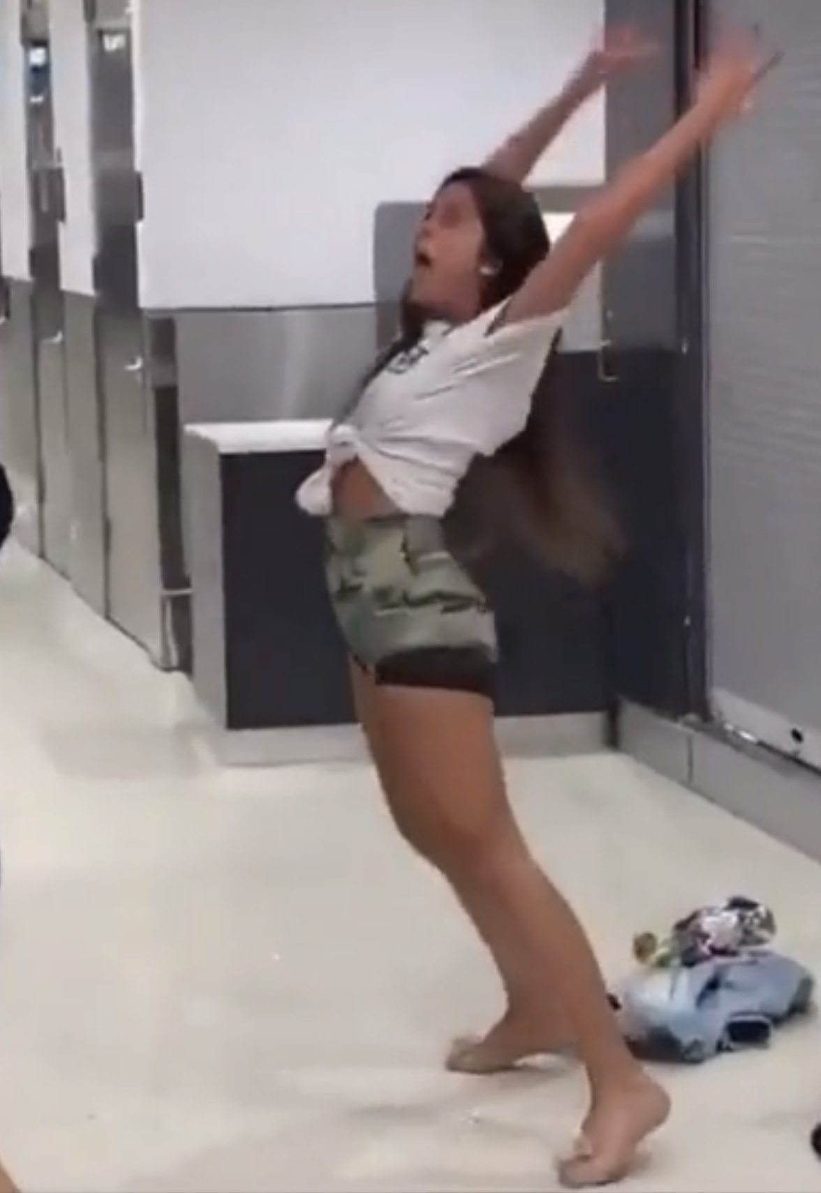 a girl in a white shirt and shorts jumping in a bathroom