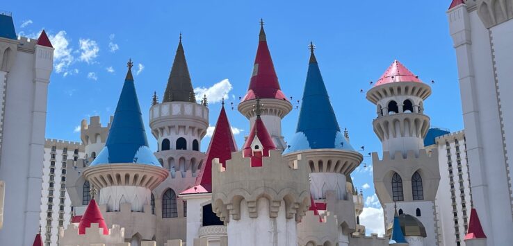 a castle with towers and towers with Excalibur Hotel and Casino in the background